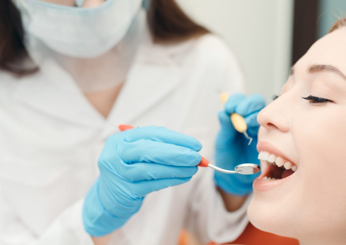 Dentist,In,A,Medical,Mask,And,Gloves,Brushing,Teeth,Of